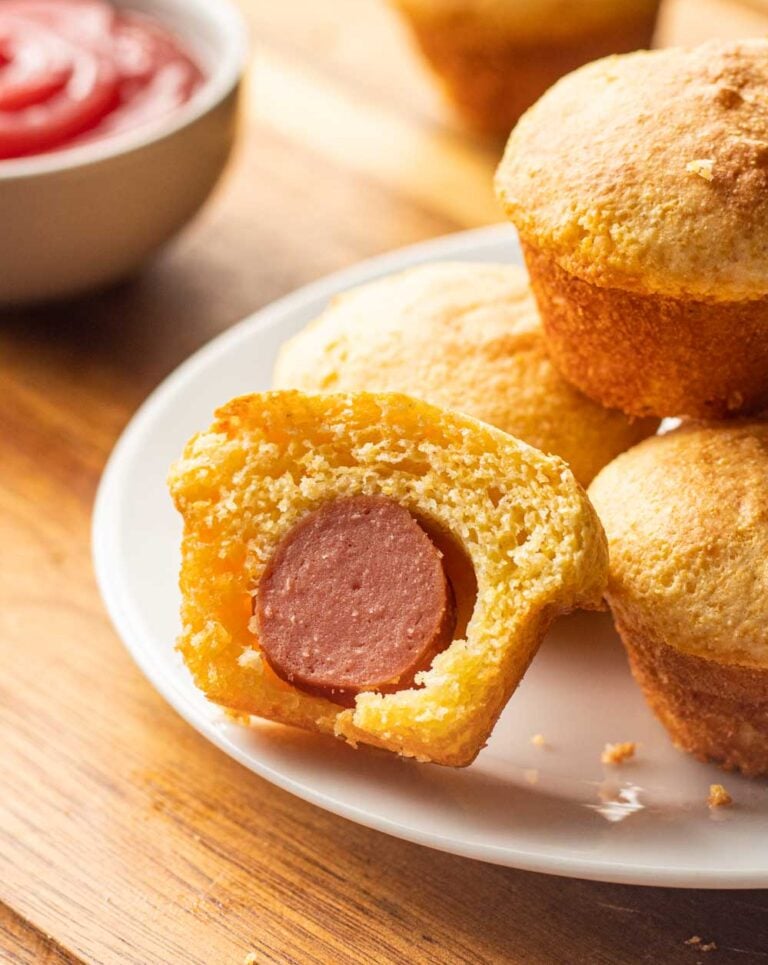 white plate with mini corn dog nuggets and a side of ketchup.