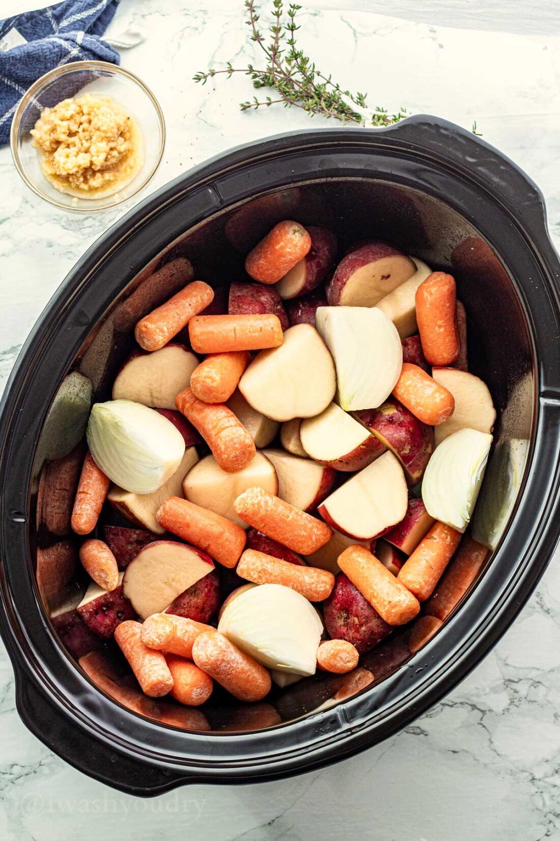 slow cooker with potatoes, carrots and onions.