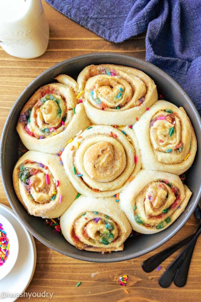 baked cinnamon rolls in pan with sprinkles.