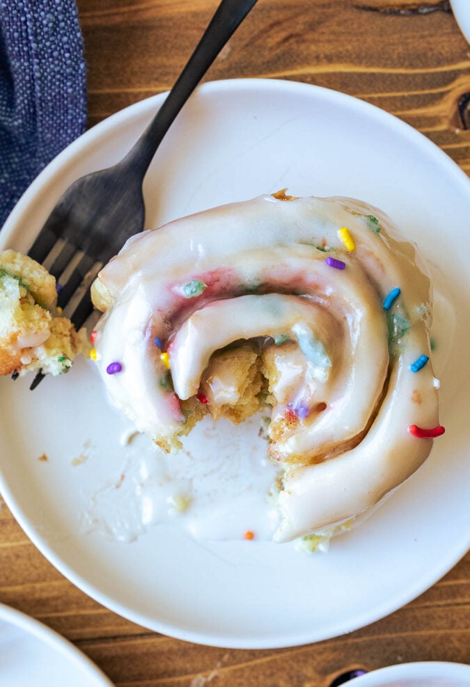 white plate with cinnamon roll and sprinkles