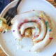 white plate with cinnamon roll and sprinkles