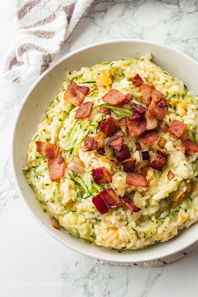 Bowl of cheesy zucchini rice with bacon.