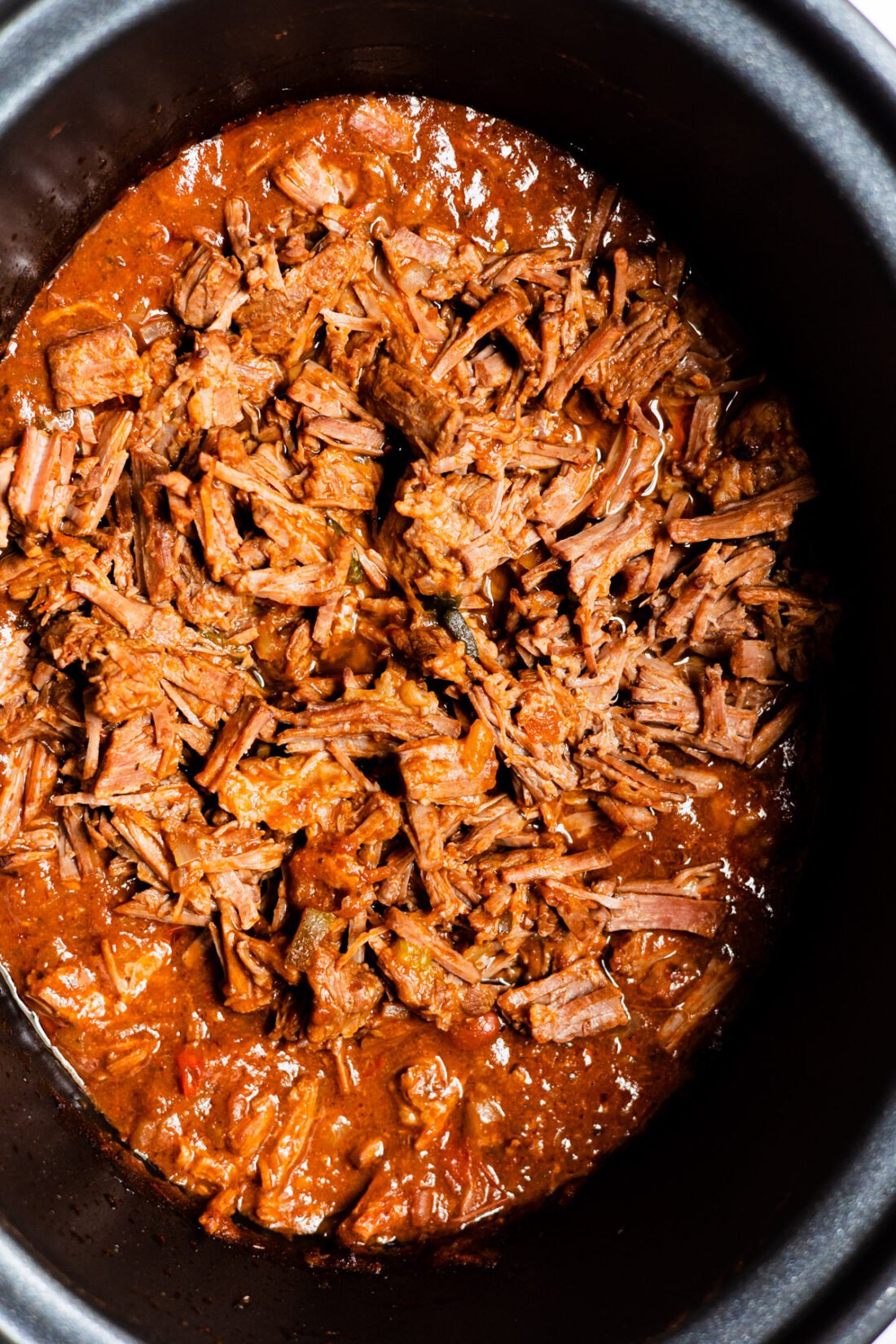 crock pot beef in slow cooker with red sauce.