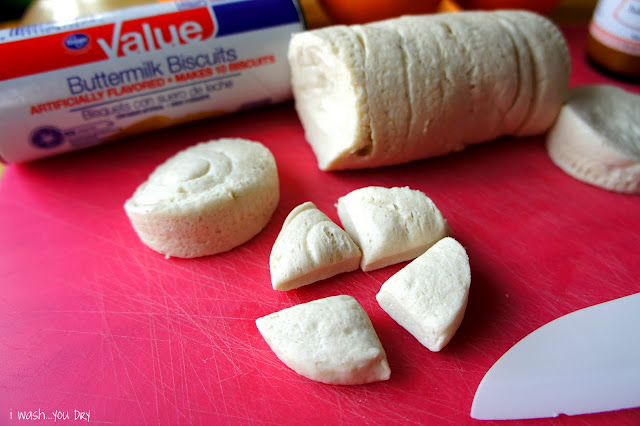 A slice of refrigerator biscuits cut into fourths displayed in front of a log of biscuit dough