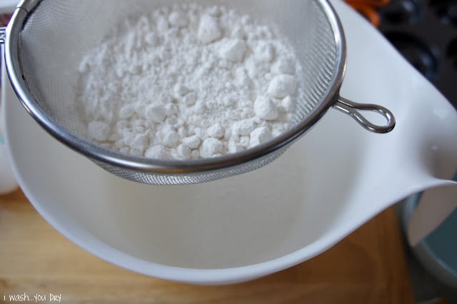 A sifter with white powder over a bowl