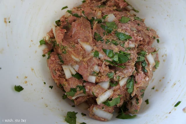 Raw meat in a bowl seasoned with onions and herbs