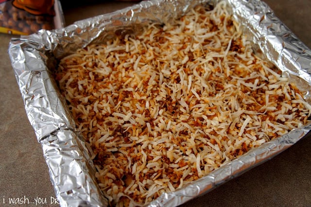 Shredded coconut layer on the cake bars in a tinfoil lined pan