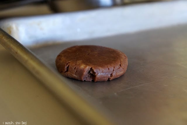 A flattened ball of cookie dough on a baking sheet