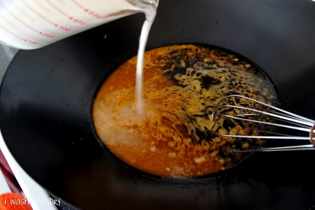 Cornstarch liquid being poured into a skillet with a brown sauce