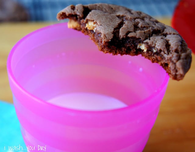 A chocolate cookie resting next to a glass of milk
