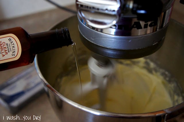 A bottle of clear vanilla adding a little into a mixing bowl mixing batter