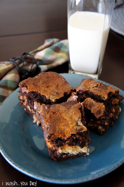 Three brownie squares on a plate next to a glass of milk