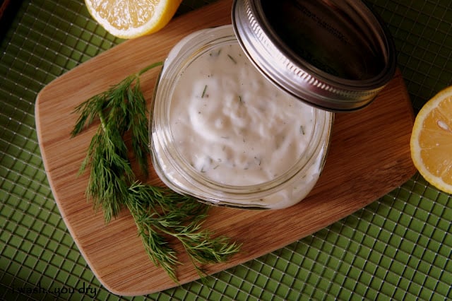 A close up of a small jar of Creamy Dill Dressing displayed on a table