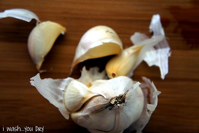 A close up of a bulb of garlic with cloves broken off of it displayed on a table