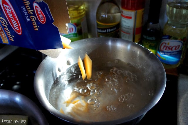 Penne pasta being added to a pot of boiling water.