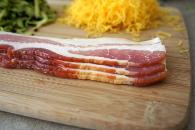 Four slices of raw bacon on a cutting board