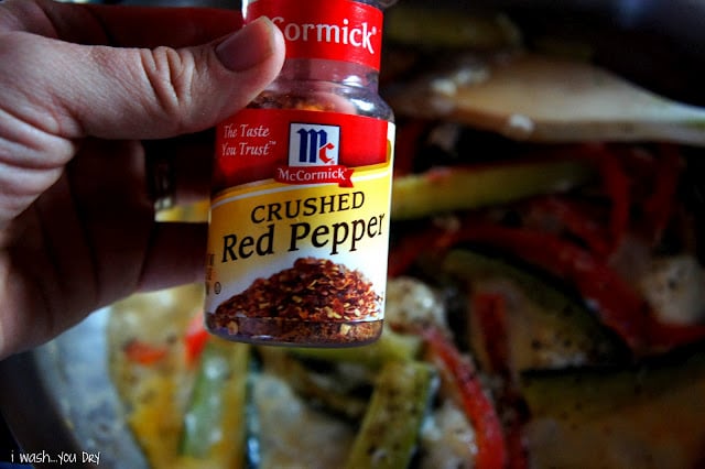 A close up of a hand holding a bottle Crushed Red Pepper.