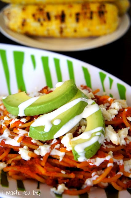 Close up of avocado slices on top of Mexican Pasta with Chorizo topped with a white sauce and cheese