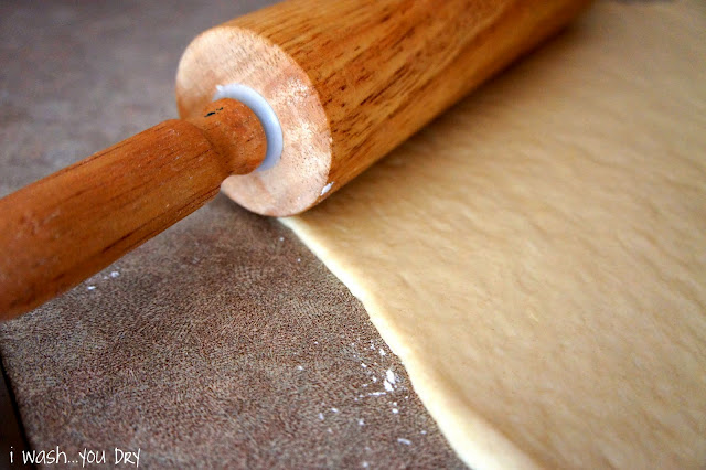 A rolling pin flattening dough for cinnamon rolls