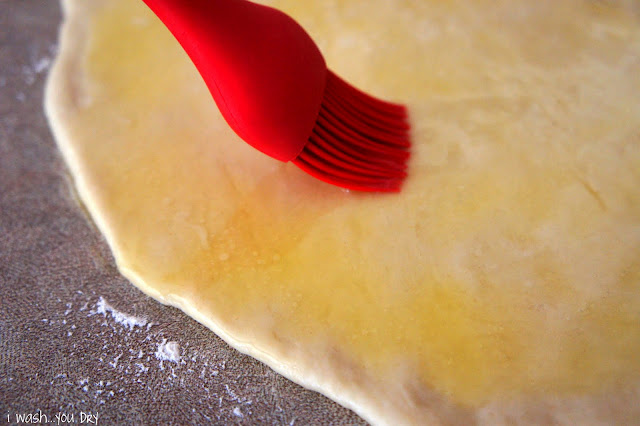 Melted butter being spread onto flattened dough