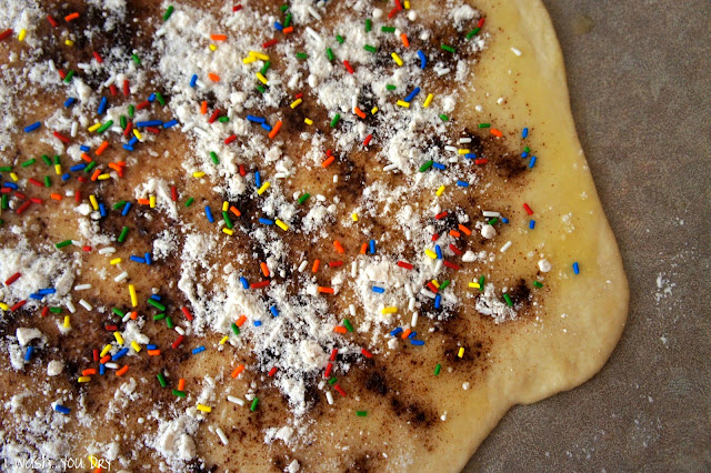 Flattened dough topped with cinnamon and sprinkles