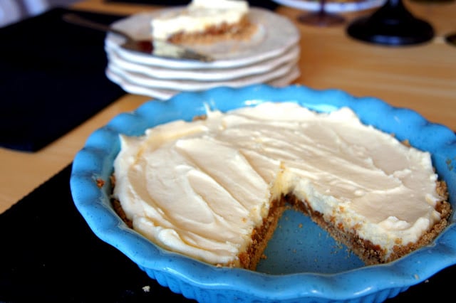 Dulce de Leche Cheesecake in a blue pie dish with a slice removed