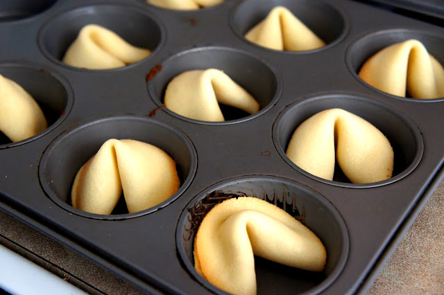 A muffin tin filled with shaped fortune cookies