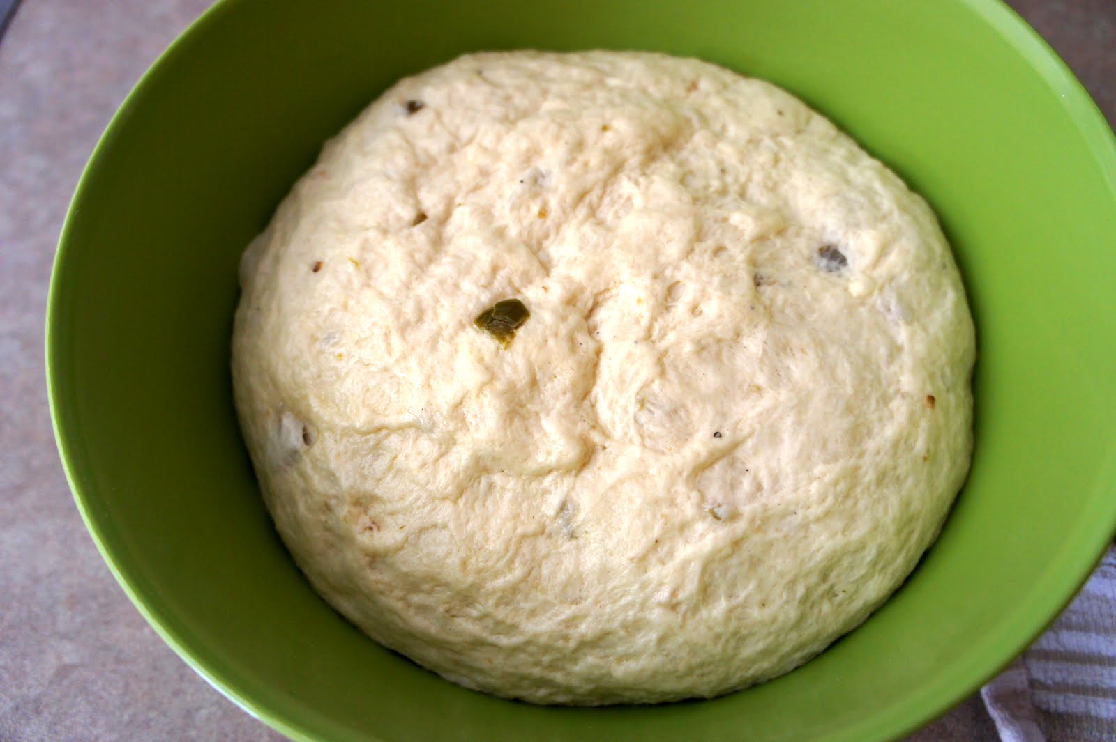 A close up of Jalapeño Cheddar Bagel dough in a bowl, after it has been rising