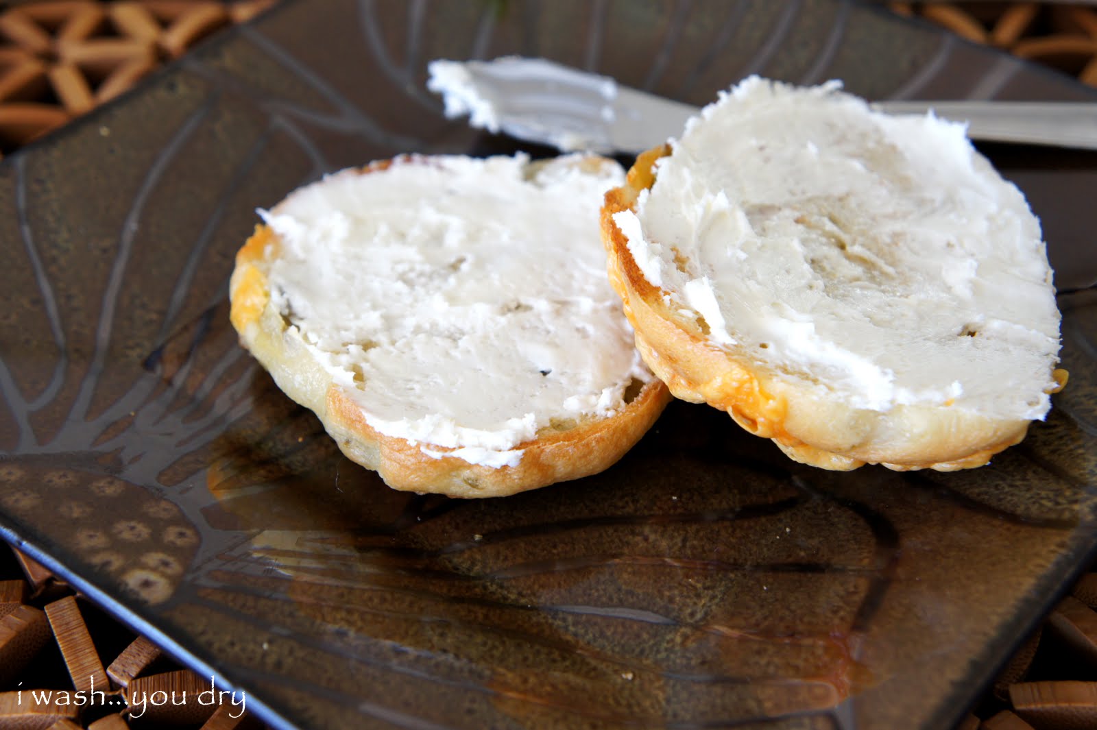 A bagel sliced in half with cream cheese spread on it, displayed on a plate