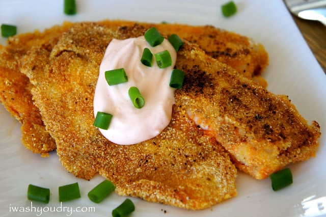 A close up of Pan Fried Cajun Tilapia topped with sour cream and chives