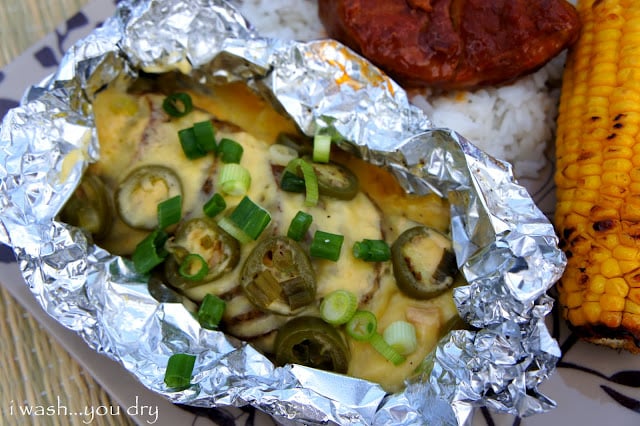 A close up of the finished product of Tinfoil Baked Potatoes, topped with cheese, olives and chives