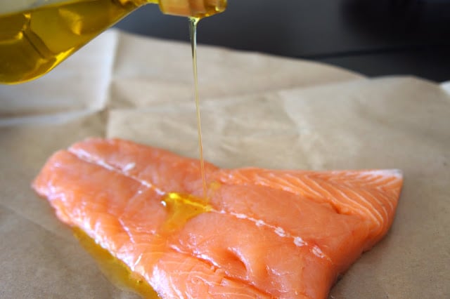 Olive oil being drizzled onto a salmon fillet