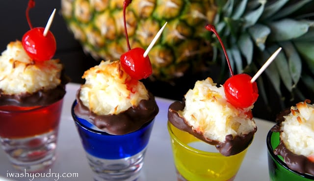 A close up of a Chocolate Dipped Pina colada Macaroons displayed on a colorful shot glass.