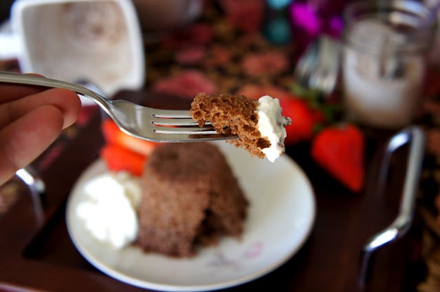 A close up of a fork with a bit of chocolate mug cake and whipped topping on it 