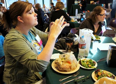 A woman taking pictures of her food while attending Camp Blogaway 2012