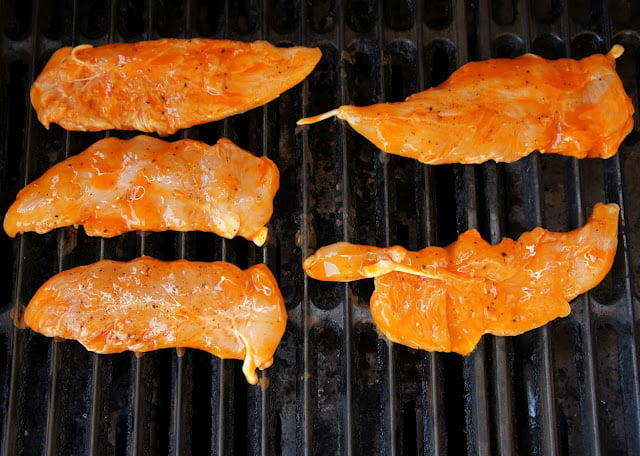 Raw chicken cooking on a grill