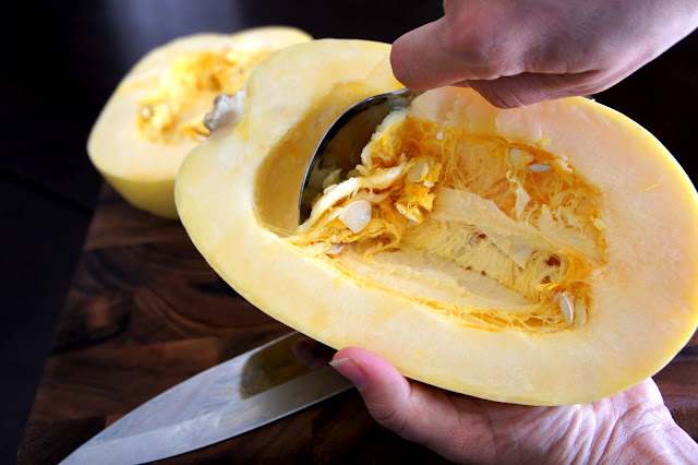 A spoon scooping the seeds from the center of a spaghetti squash
