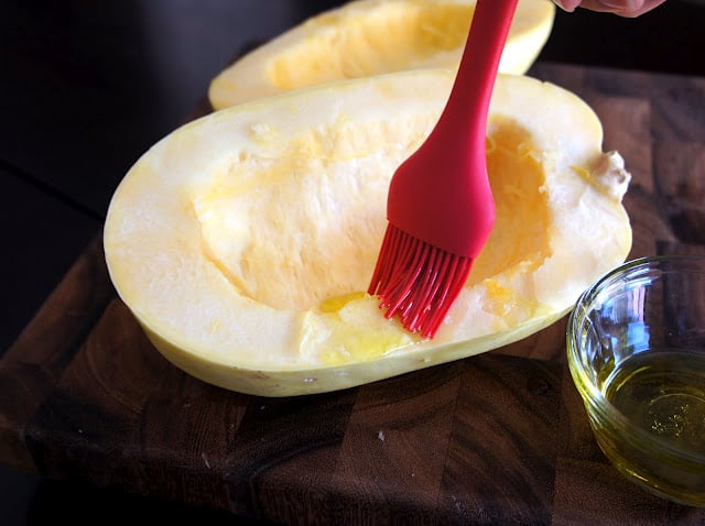 A pastry brush spreading olive oil on the spaghetti squash