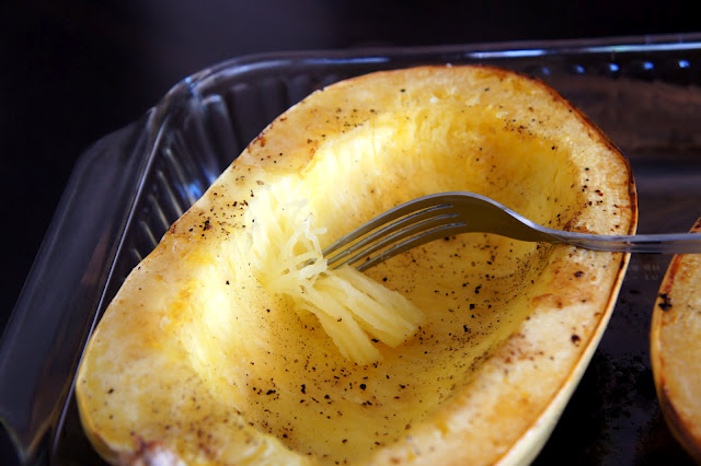 Baked spaghetti squash in a pan with a fork starting to shred it