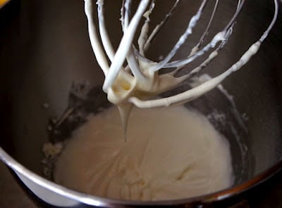 A close up of beaters over a white liquid mixture in a mixing bowl