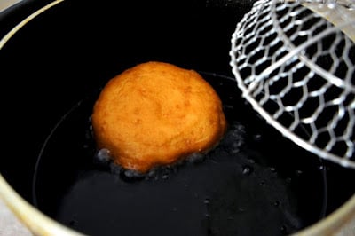 A close up of a fried biscuit in a pan of oil