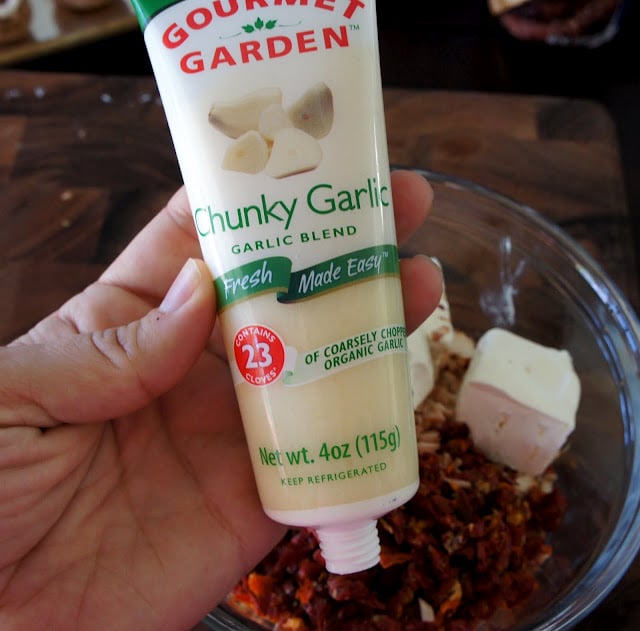 A hand holding a bottle of herbs titled, \"Gourmet Garden: chunky Garlic\"