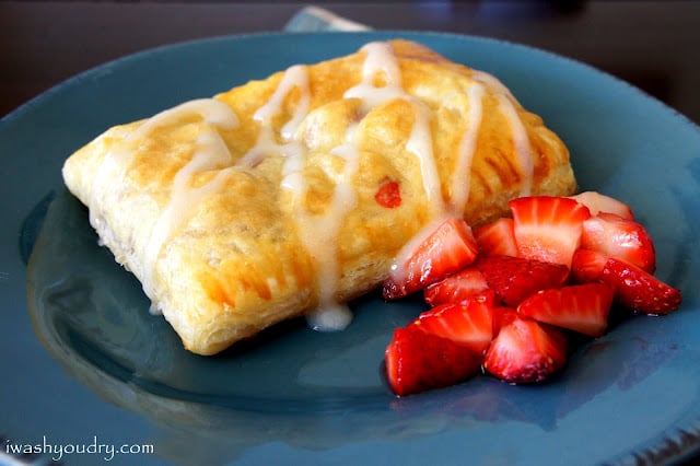 A close up of a Homemade Strawberry and Cream Cheese Toaster Strudel on a plate, with a side of diced strawberries