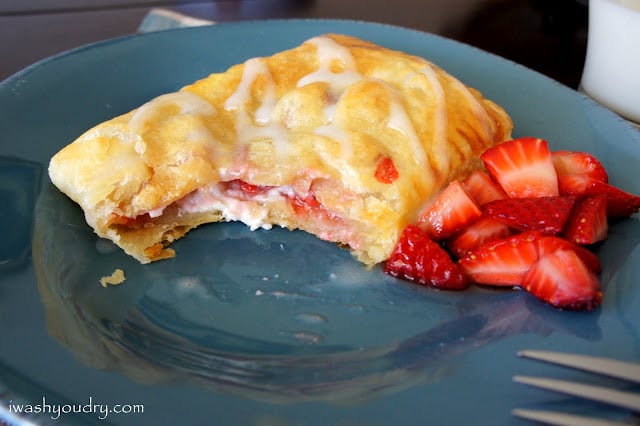 A close up of a Homemade Strawberry and Cream Cheese Toaster Strudel on a plate, with a bit removed from the strudel. 