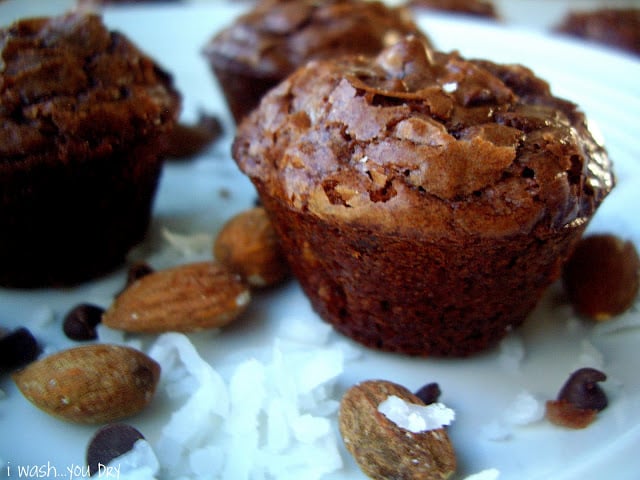 A close up of a mini brownie bite surrounded by almonds. 