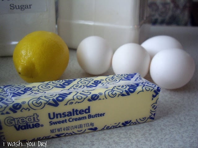 A display of a lemon, a stick of butter and four eggs. 