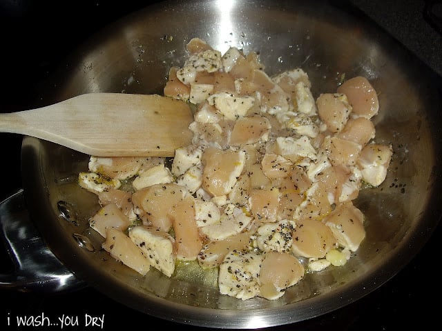 Raw chicken cooking in a pan with seasoning. 
