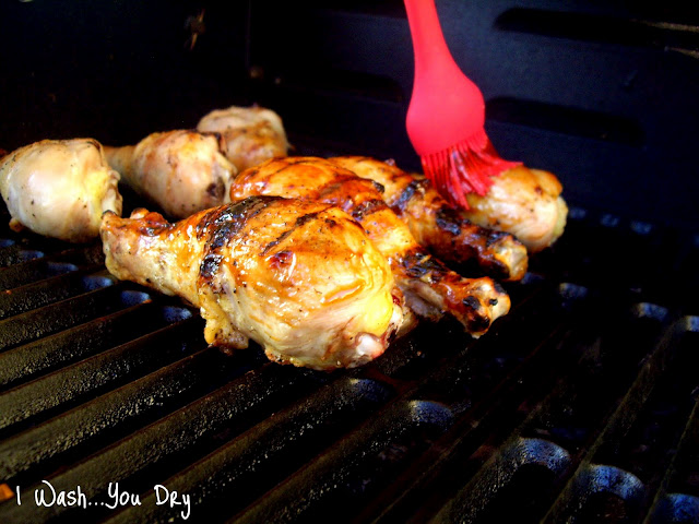 A pastry brush adding sauce on chicken cooking on a grill. 