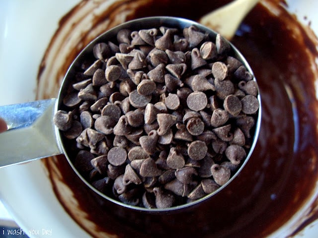 A measuring cup of chocolate chips above a bowl of chocolate batter.