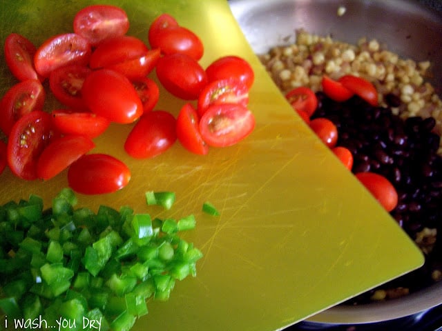 A cutting board of diced veggies being added to a pan.